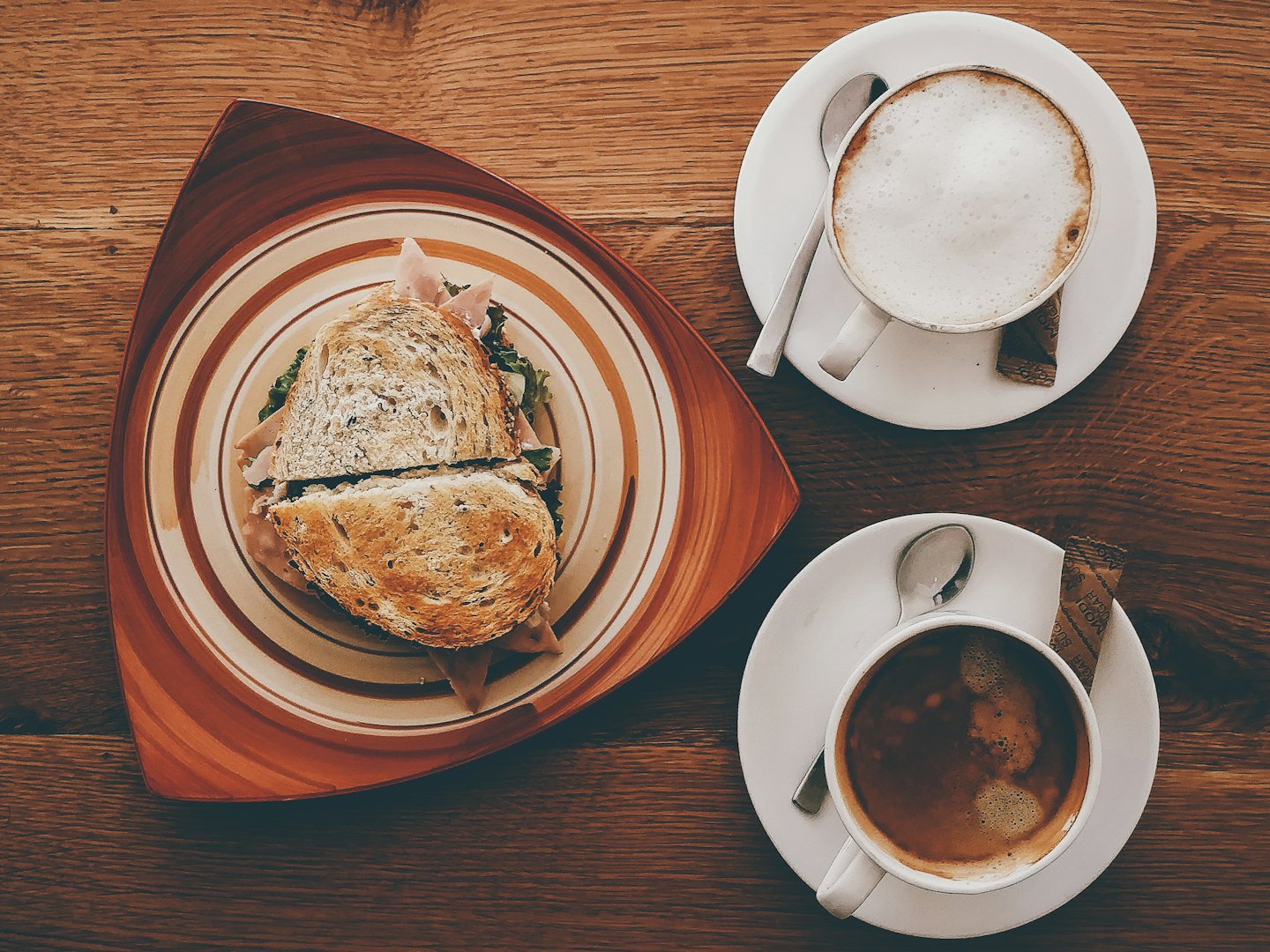 Sliced sandwich and coffee cups on a rustic table.