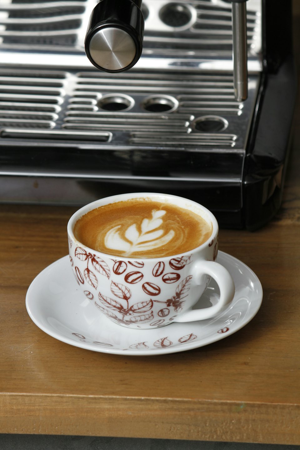 Cup of coffee with leaf art on a wooden counter.