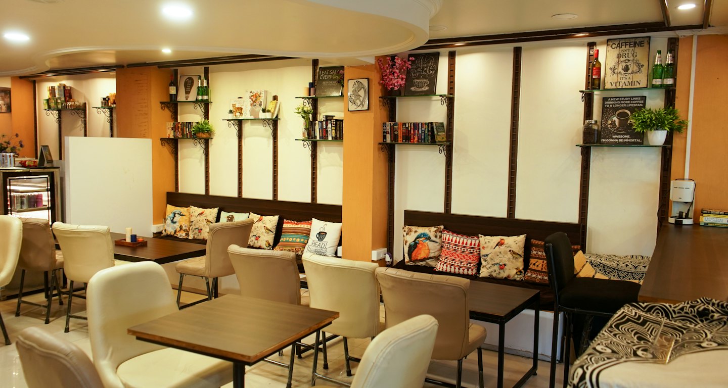 Tables and seating area in a cozy cafe with shelves.